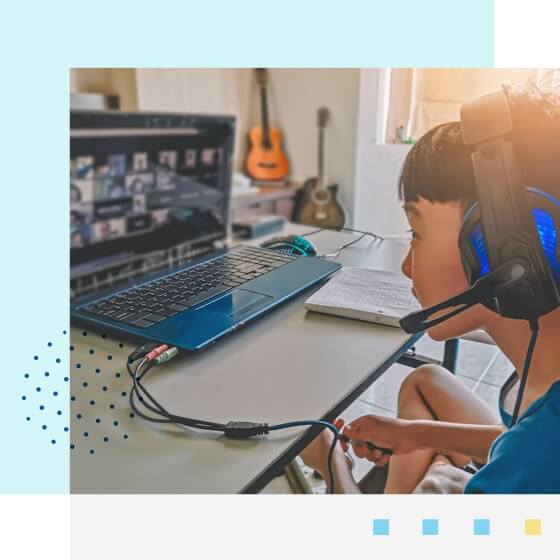 Elementary student wearing his headset and attending an online class with his laptop