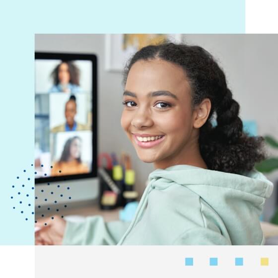 Student smiling at the camera attending an online class at her home